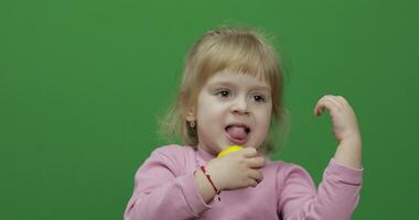 mooi jong meisje eet een citroen met een grijns Aan haar gezicht. chroma sleutel video