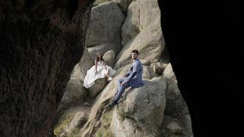 Groom with bride sit on a high slope of the mountain. Wedding couple. Happy video