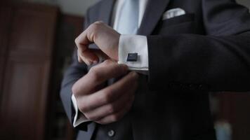 Handsome groom man fixes his cuffs on a jacket with cufflinks. Businessman video