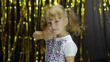 niño baile, disfrutando música, Moviente en lento ritmo bailar. niña 4-5 años antiguo en brillante camiseta video