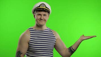 Young sailor man shows something with hands. Seaman guy in sailor's vest video