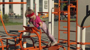 joven niña en ropa de deporte haciendo Lagartijas ejercicios en patio de juegos. rutina de ejercicio para niños. atlético niño video