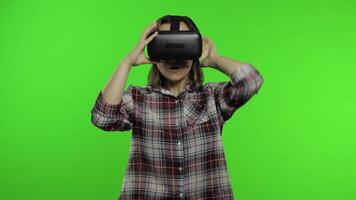 Young girl using VR app helmet to play simulation game. Woman watching virtual reality 3d video