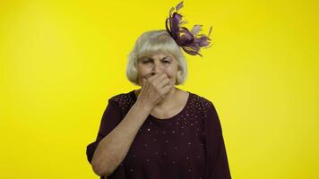 Senior old woman zipping lips and looking scared, covering mouth promising to keep secret, silence video