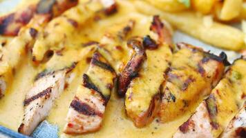 sliced chicken with cream sauce with french fries on a plate . video