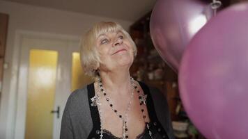 süß Oma feiert ihr Geburtstag. hält mehrfarbig Luftballons im ihr Hände video