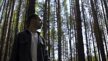 Relaxed man spending time outdoors in summer forest. Stock footage. Portrait of pensive guy enjoying walk in park. photo