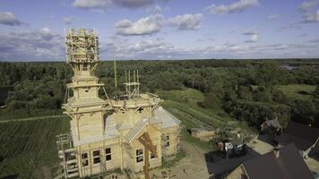 Top view of construction of wooden building with tower. Stock footage. Construction or restoration of old Russian wooden church. Construction of wooden temple on background of summer forest photo