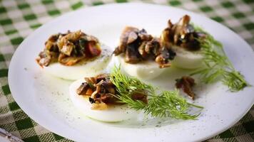 boiled eggs stuffed with mushrooms and spices in a plate on a wooden table. video