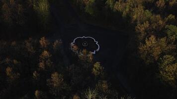 Top view of fountain and roads in autumn forest. Clip. Roads intersect in center with fountain. Crossroads with fountain in autumn forest on cloudy day photo