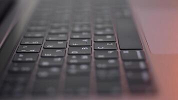 perspectiva de un moderno computadora o ordenador portátil negro teclado en rosado fondo, cerca arriba vista. acción. nuevo teclado con negro botones y blanco símbolos en a ellos, moderno tecnologías concepto. foto