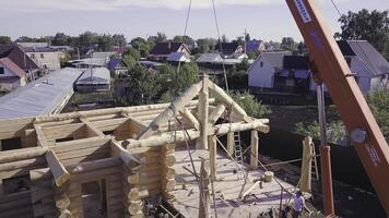 Workers with crane lift wooden structure of house. Clip. Top view of process of installing facade of wooden roof with help of workers and crane photo