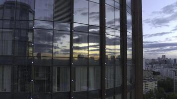 Top view of sunset reflection in windows of business high-rise. Stock footage. Modern skyscraper with glass windows and reflection. Reflection of city and sunset in windows of business building photo