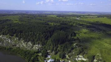 Top view of village on river bank on background of horizon with forest. Clip. Beautiful summer landscape with village on river bank and green forest. Houses by river on background of horizon of green photo