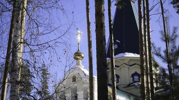 Winter landscape with snow-covered trees against the background of a Christian church after a snowfall. Frosty sunny day photo