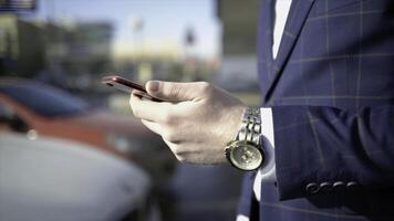 Close-up of businessman pressing car key. Action. Businessman opens car with electronic key and looks at phone. Modern car key to open and start it photo