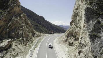 Top view of mountain road with driving car in summer. Action. Car trip on mountain roads on summer day. Beautiful trip along mountain serpentine on sunny day photo