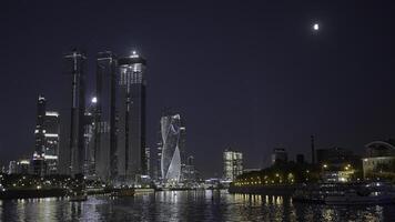 Moscow 2021. Action. Beautiful huge evening buildings near the river in Moscow were shot from afar on a dark evening with bright lights and lanterns that glow . photo