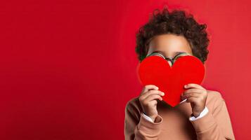 AI generated A shy little boy holding a paper heart shape and hiding behind it on grey background photo