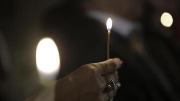 Encendiendo un vela con un partido a obtener un romántico luz de una vela. increíble andles y candelabros son en el mesa. permanecer luces con el pacífico antecedentes de religioso ceremonia. foto