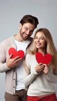 AI generated Young happy couple in love holding red paper heart isolated on grey background photo