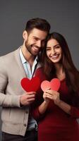 AI generated Young happy couple in love holding red paper heart isolated on grey background photo