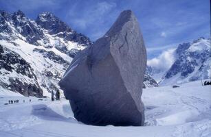 a large rock in the middle of a snowy field photo