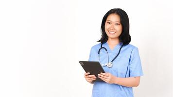 joven asiático hembra médico utilizando tableta para trabajo y sonriente aislado en blanco antecedentes foto