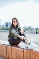 Young Beautiful Asian Woman Wearing Jacket And Black Jeans Posing Outdoors photo