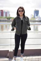 Young Beautiful Asian Woman Wearing Jacket And Black Jeans Posing Outdoors photo