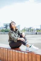 Young Beautiful Asian Woman Wearing Jacket And Black Jeans Posing Outdoors photo