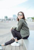 Young Beautiful Asian Woman Wearing Jacket And Black Jeans Posing Outdoors photo