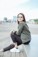 Young Beautiful Asian Woman Wearing Jacket And Black Jeans Posing Outdoors photo