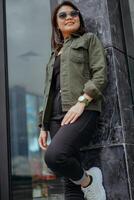 Young Beautiful Asian Woman Wearing Jacket And Black Jeans Posing Outdoors photo