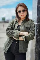 Young Beautiful Asian Woman Wearing Jacket And Black Jeans Posing Outdoors photo