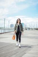 Playing Ukulele of Young Beautiful Asian Woman Wearing Jacket And Black Jeans Posing Outdoors photo