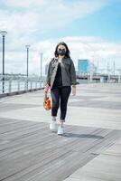 Playing Ukulele of Young Beautiful Asian Woman Wearing Jacket And Black Jeans Posing Outdoors photo