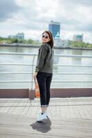 Playing Ukulele of Young Beautiful Asian Woman Wearing Jacket And Black Jeans Posing Outdoors photo