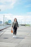 Playing Ukulele of Young Beautiful Asian Woman Wearing Jacket And Black Jeans Posing Outdoors photo