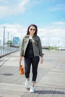 Playing Ukulele of Young Beautiful Asian Woman Wearing Jacket And Black Jeans Posing Outdoors photo