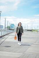 Playing Ukulele of Young Beautiful Asian Woman Wearing Jacket And Black Jeans Posing Outdoors photo