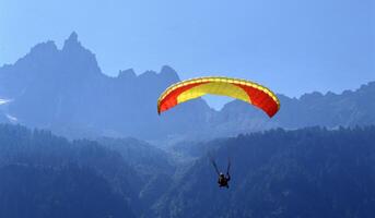 a person is flying a parachute over a mountain photo
