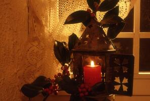 a candle is lit in a lantern with berries and leaves photo