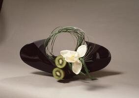 a black vase with a flower and kiwi photo