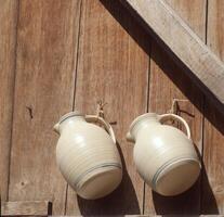 two white jugs hanging on a wooden wall photo