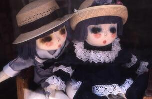 two dolls sitting in a window photo