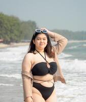 Portrait young asian woman fat chubby cute beautiful smile happy fun bikini swimwear body sexy front view tropical sea beach white sand clean and bluesky calm nature ocean wave water travel on holiday photo