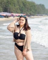 Portrait young asian woman fat chubby cute beautiful smile happy fun bikini swimwear body sexy front view tropical sea beach white sand clean and bluesky calm nature ocean wave water travel on holiday photo