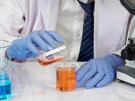 Portrait asian man student scientist Wearing a doctor gown in the lab looking hand at chemist. caused by mixing reagents in scientific research laboratories with test tubes and microscope on the table photo