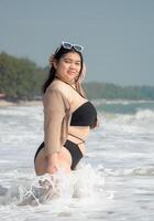 Portrait young asian woman fat chubby cute beautiful smile happy fun bikini swimwear body sexy front view tropical sea beach white sand clean and bluesky calm nature ocean wave water travel on holiday photo